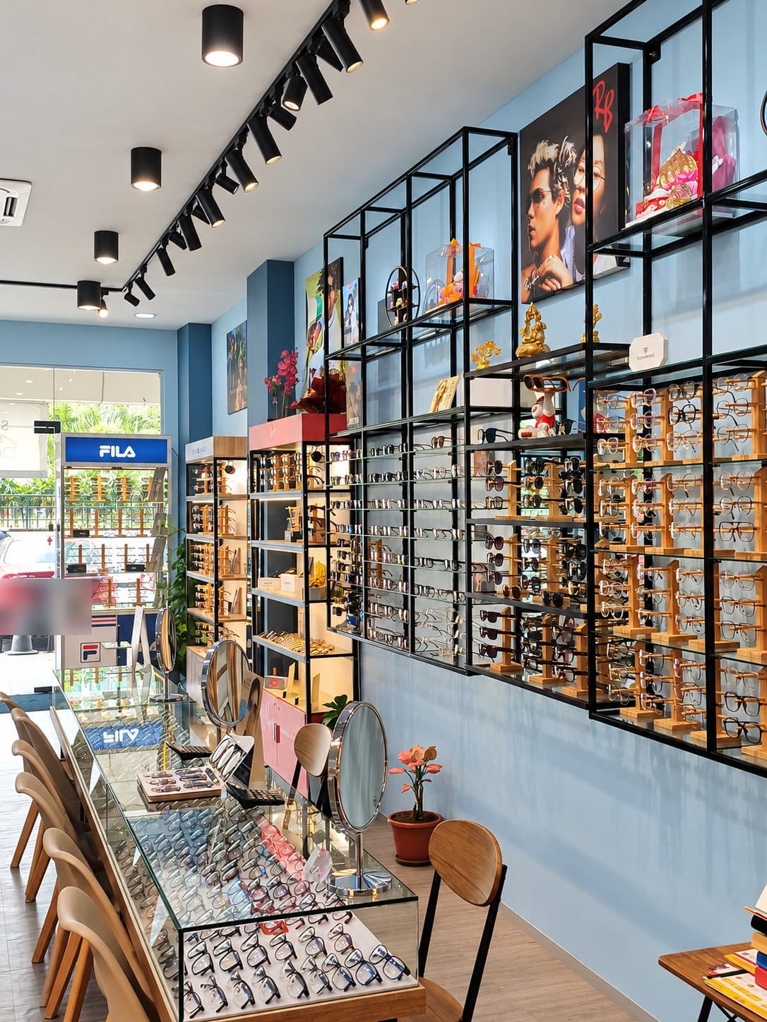 The frame wall at Visionary Eyecare: black steel shelves of spectacles and sunglasses above a glass display counter