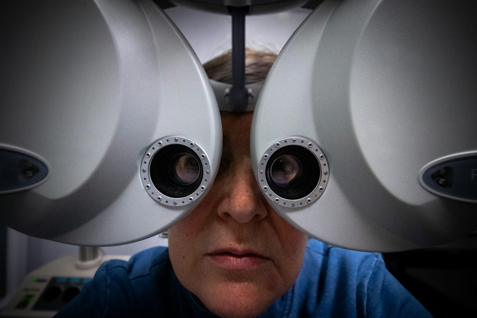 A patient looking through a phoropter, the instrument used to compare lenses during an eye examination